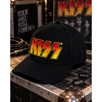 Casquette KISS noire avec logo brodé rouge, orange et jaune dans un décor backstage rock | Black KISS cap with red, orange and yellow embroidered logo in a rock backstage setting