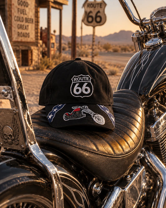 Casquette Route 66 noire avec motif moto posée sur une selle de custom | Black Route 66 motorcycle cap displayed on a custom bike seat
