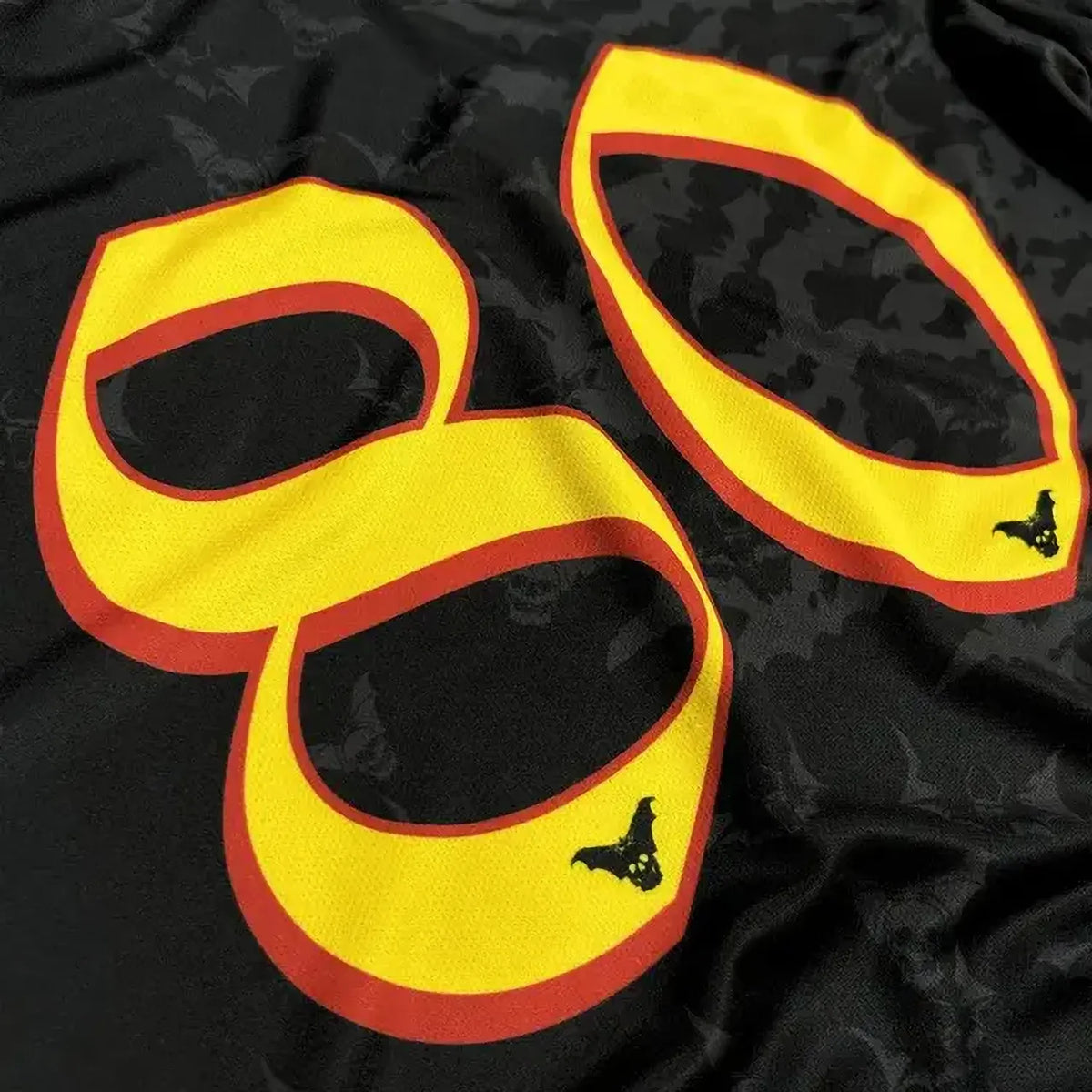 Détail du numéro 80 jaune et rouge au dos du maillot Ozzy Osbourne avec petites chauves-souris | Detail of the yellow and red number 80 on the Ozzy Osbourne shirt with small bat motifs