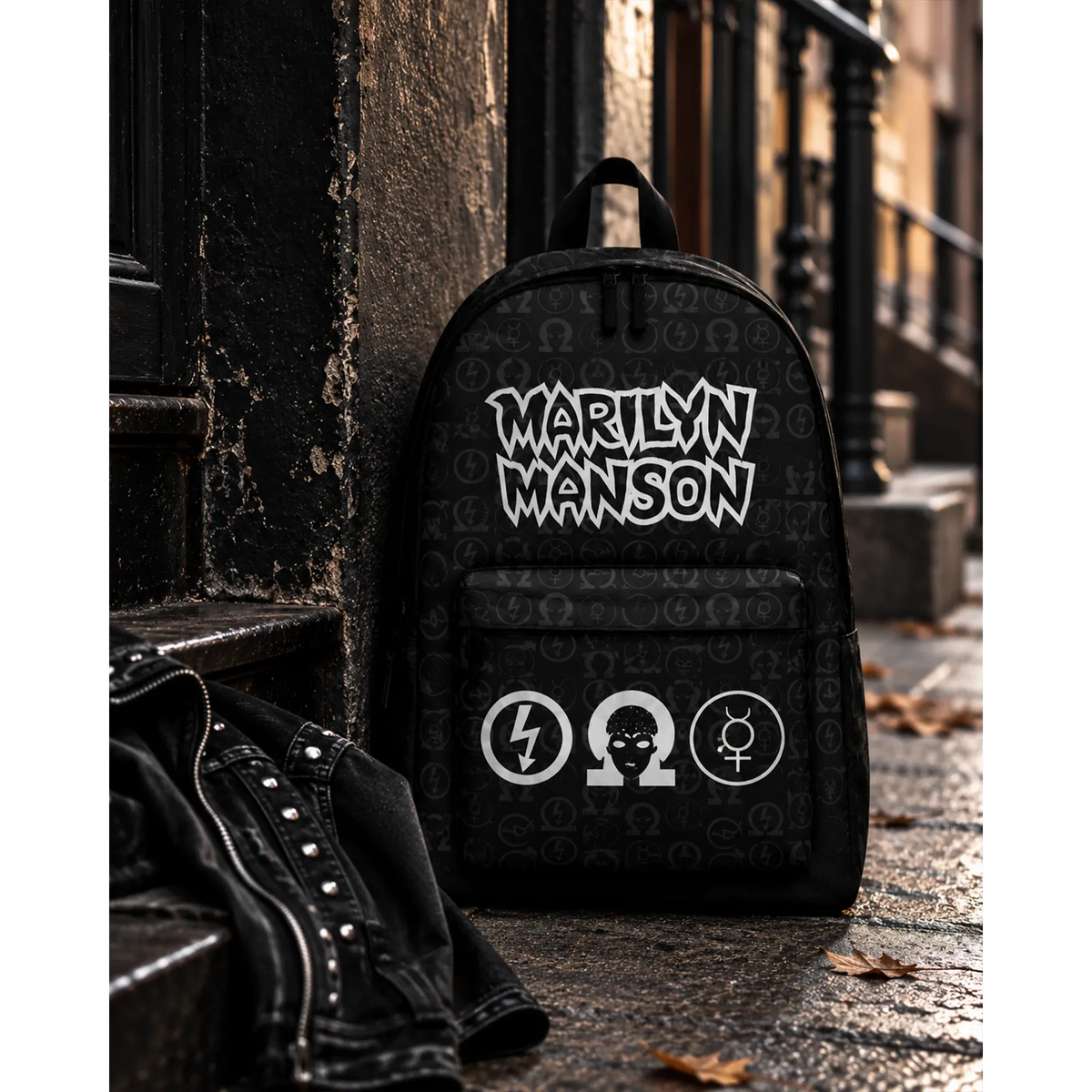 Sac à dos Marilyn Manson noir avec logo blanc et symboles graphiques en décor urbain | Black Marilyn Manson backpack with white logo and graphic symbols in an urban setting